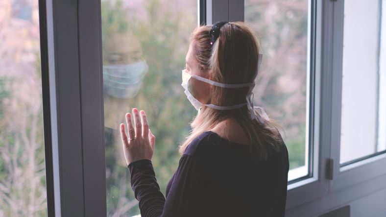 Woman with a mask on looking outside