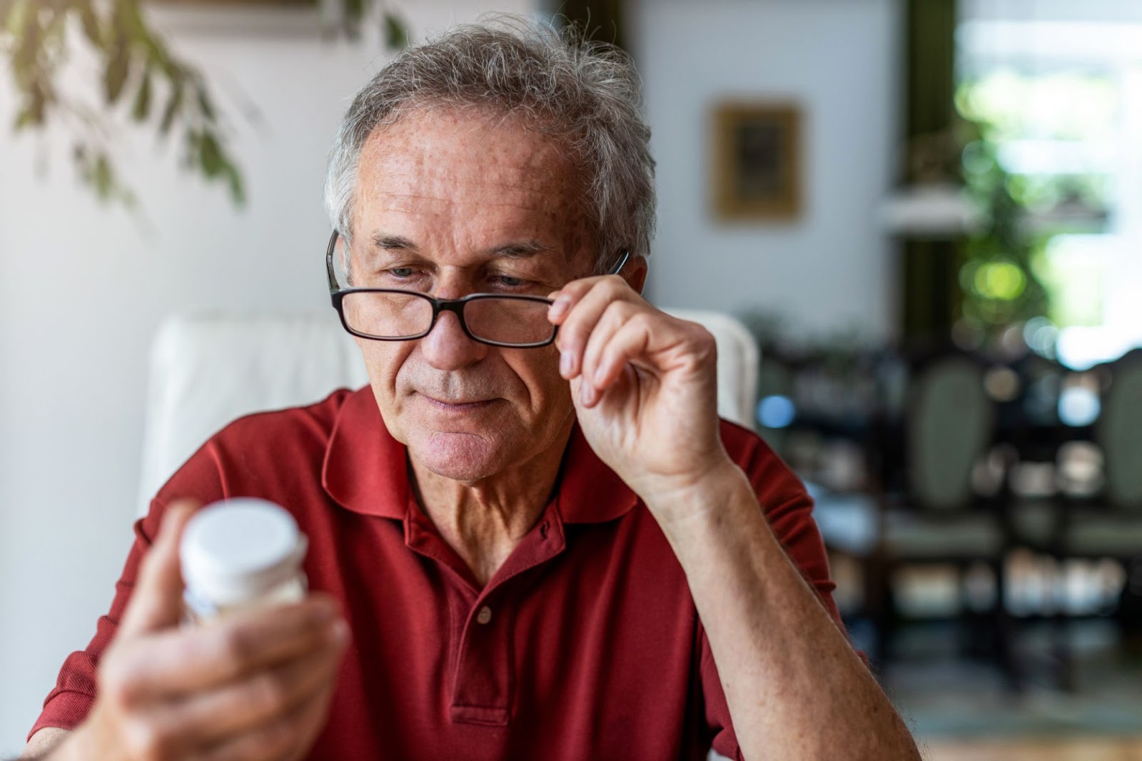 Elderly man looking at the back of the pill bottle